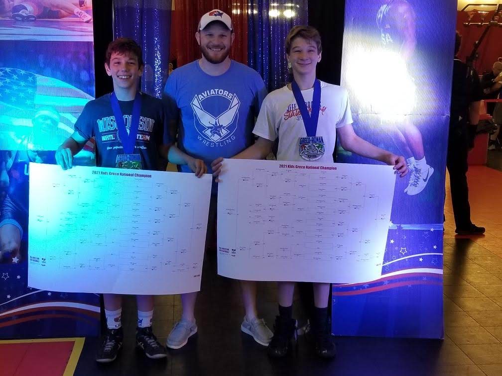 Jason with two Aviators wrestlers holding tournament bracket boards