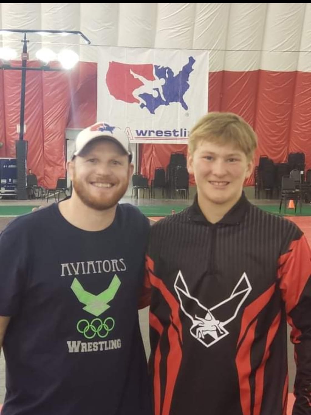 Jason standing beside an Aviators youth wrestler at a competition